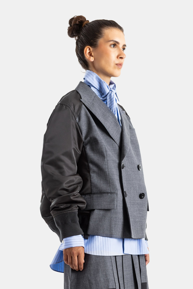 Sacai veste croisée gris chiné profil trois quarts avec nœud foulard bleu ciel et jupe plissée assortie