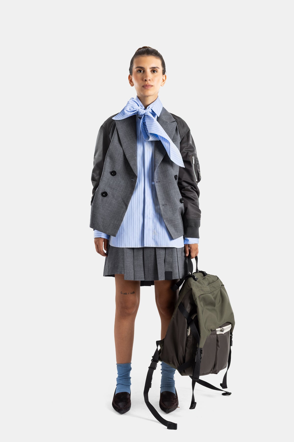 Sacai veste hybride double boutonnage boutons noirs look complet face avec sac à dos kaki et chaussettes bleues
