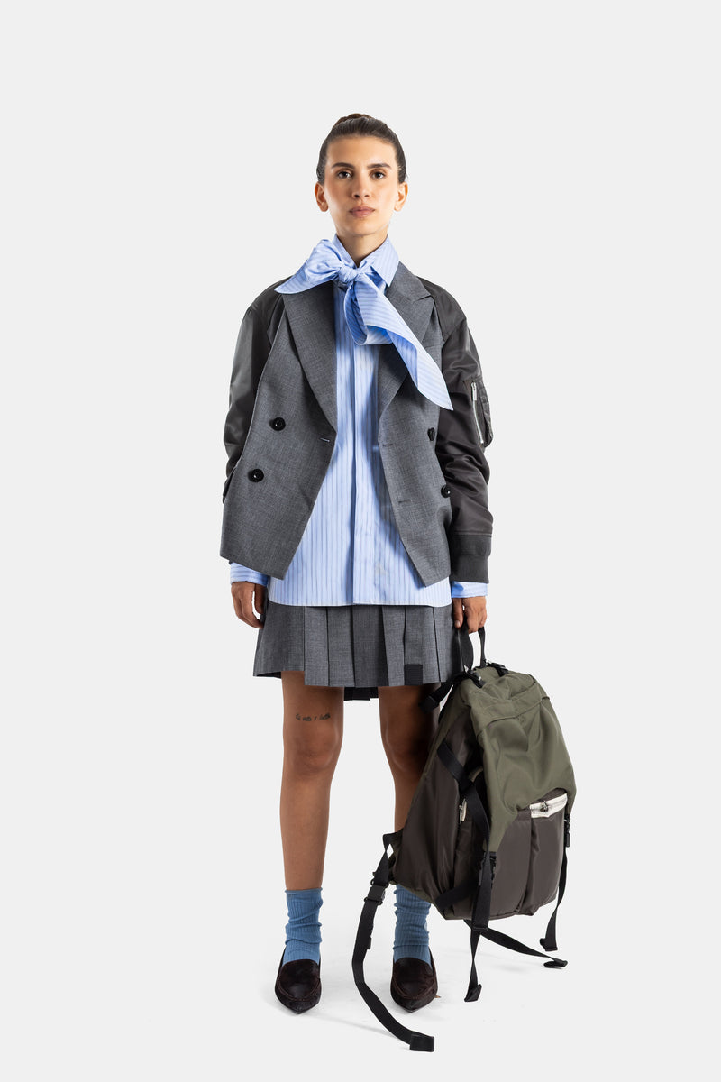 Sacai veste hybride double boutonnage boutons noirs look complet face avec sac à dos kaki et chaussettes bleues