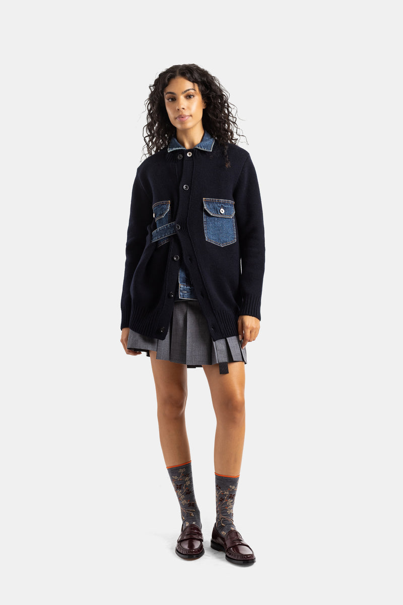 Front view of Sacai women's cardigan, layered look with gray pleated skirt and floral socks, navy knit and denim.