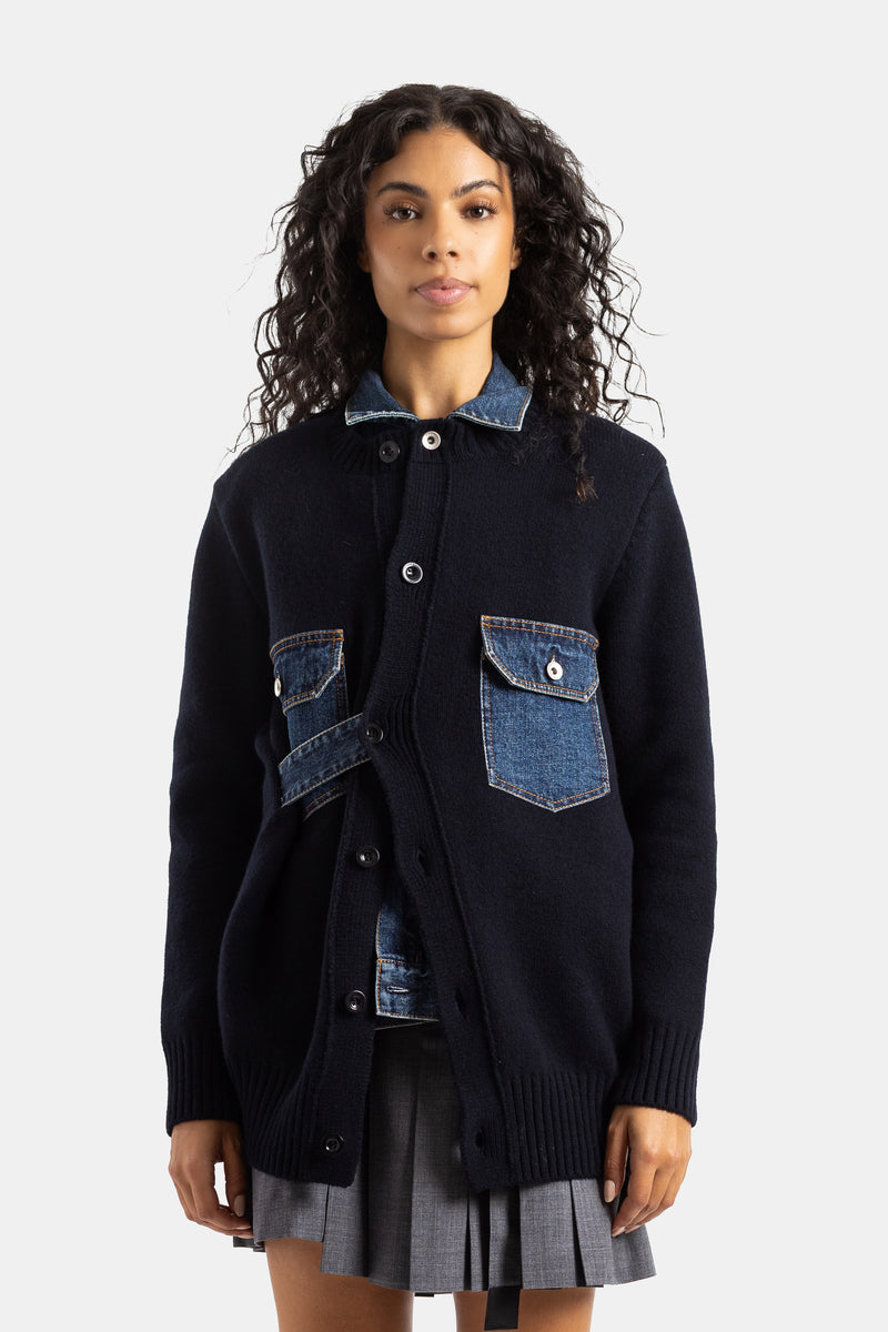 Oversized Sacai cardigan in navy blue wool knit featuring raw denim inserts and functional buttoned pockets.