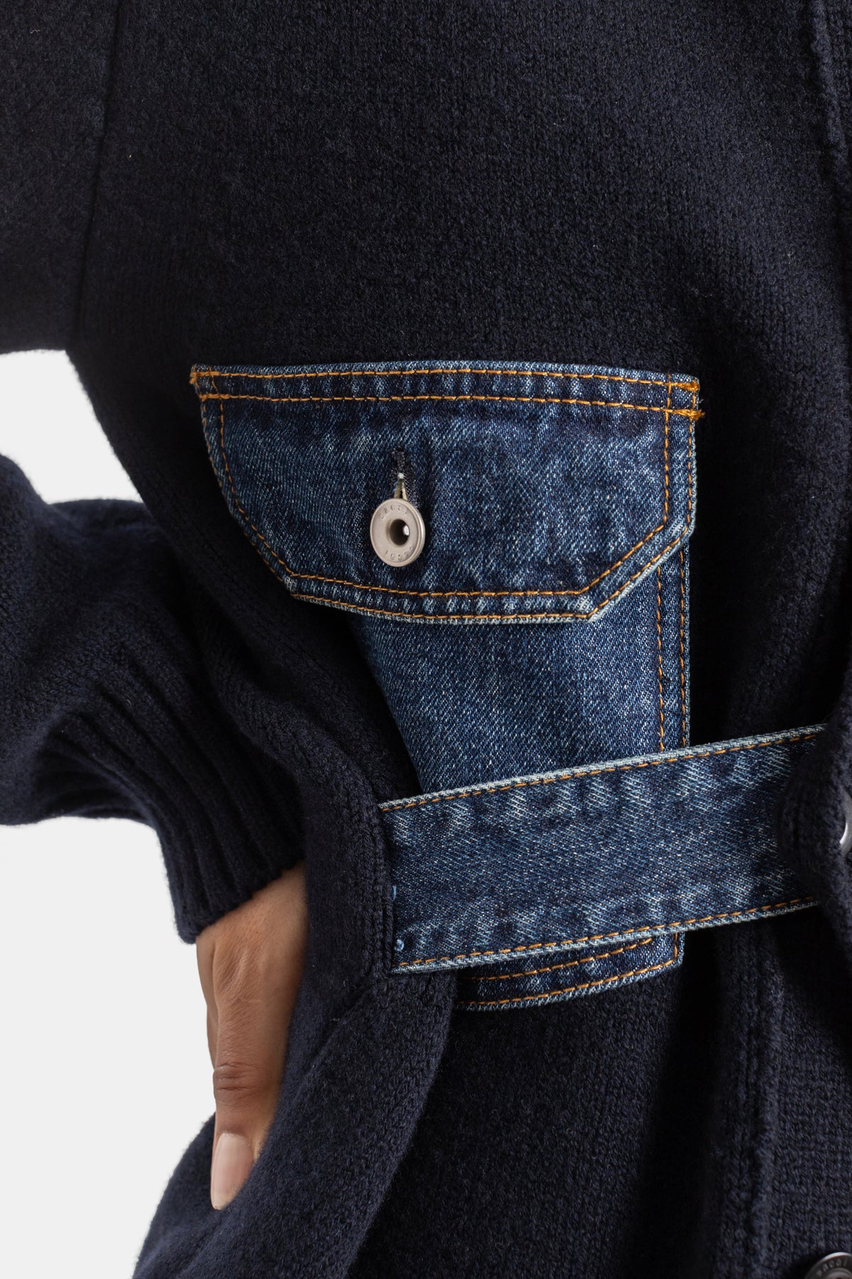Cardigan donna Sacai, focus sulla tasca cargo in denim indaco con cuciture arancioni su maglia di lana blu navy.