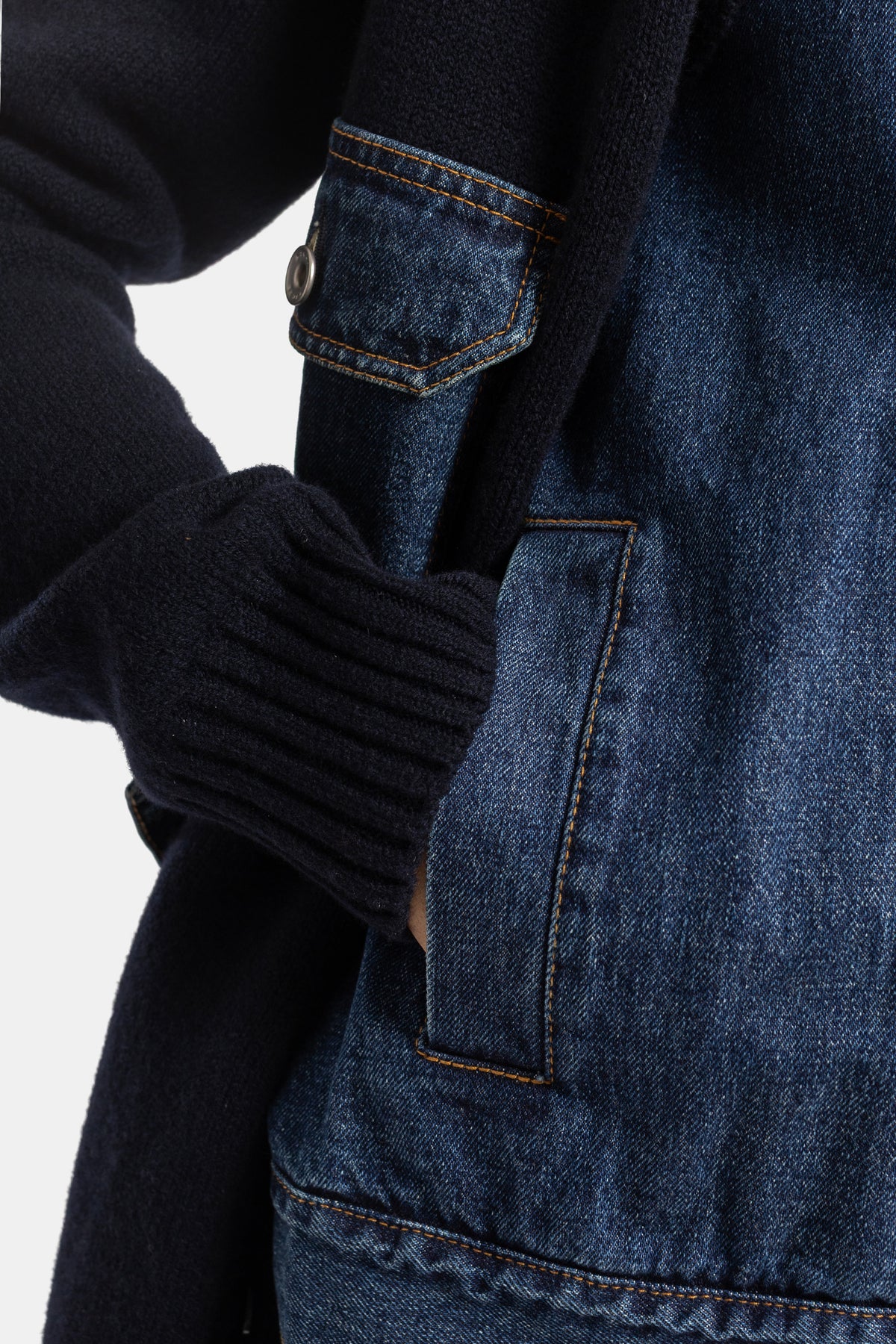 Cardigan donna Sacai, dettaglio del polsino in denim con cuciture arancioni sovrapposto a maglia a coste navy.