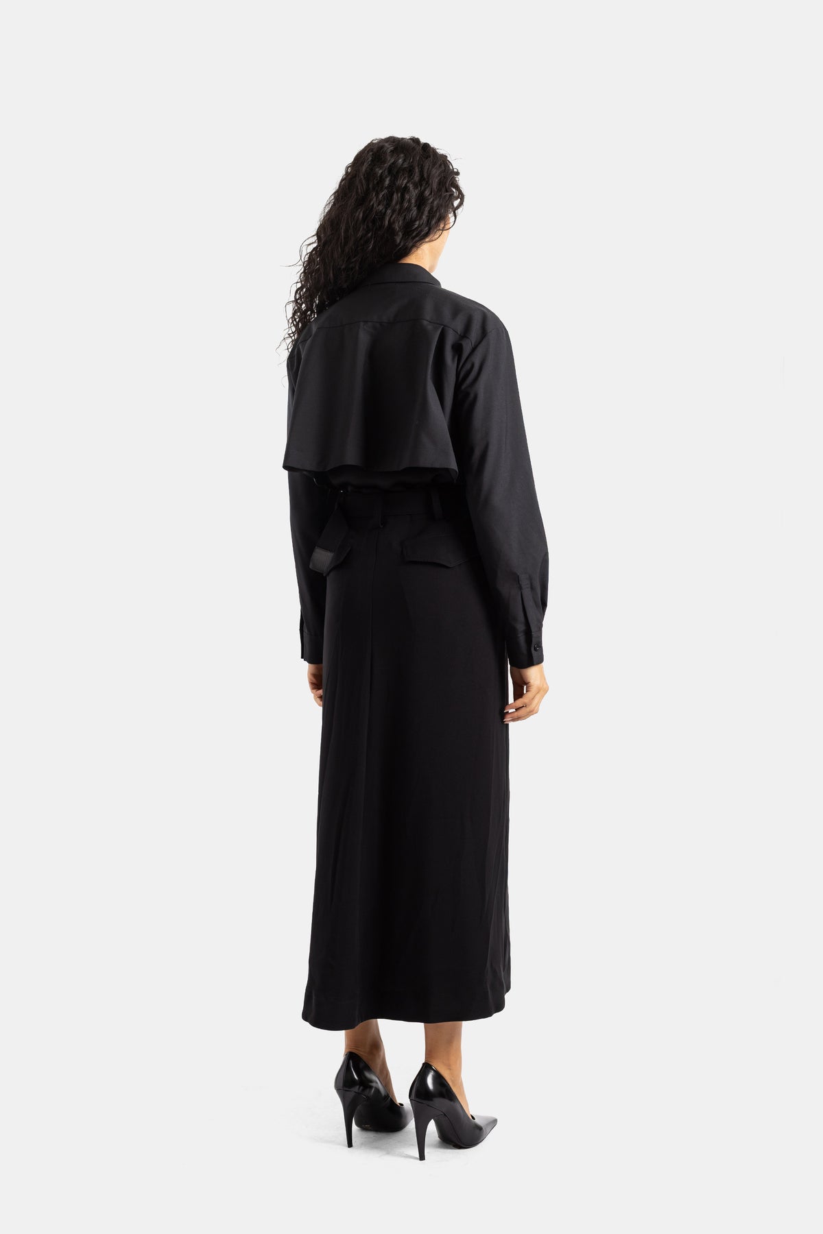 Sacai long black dress with cropped layered jacket back, knotted belt, satin crepe, and high stiletto heels.