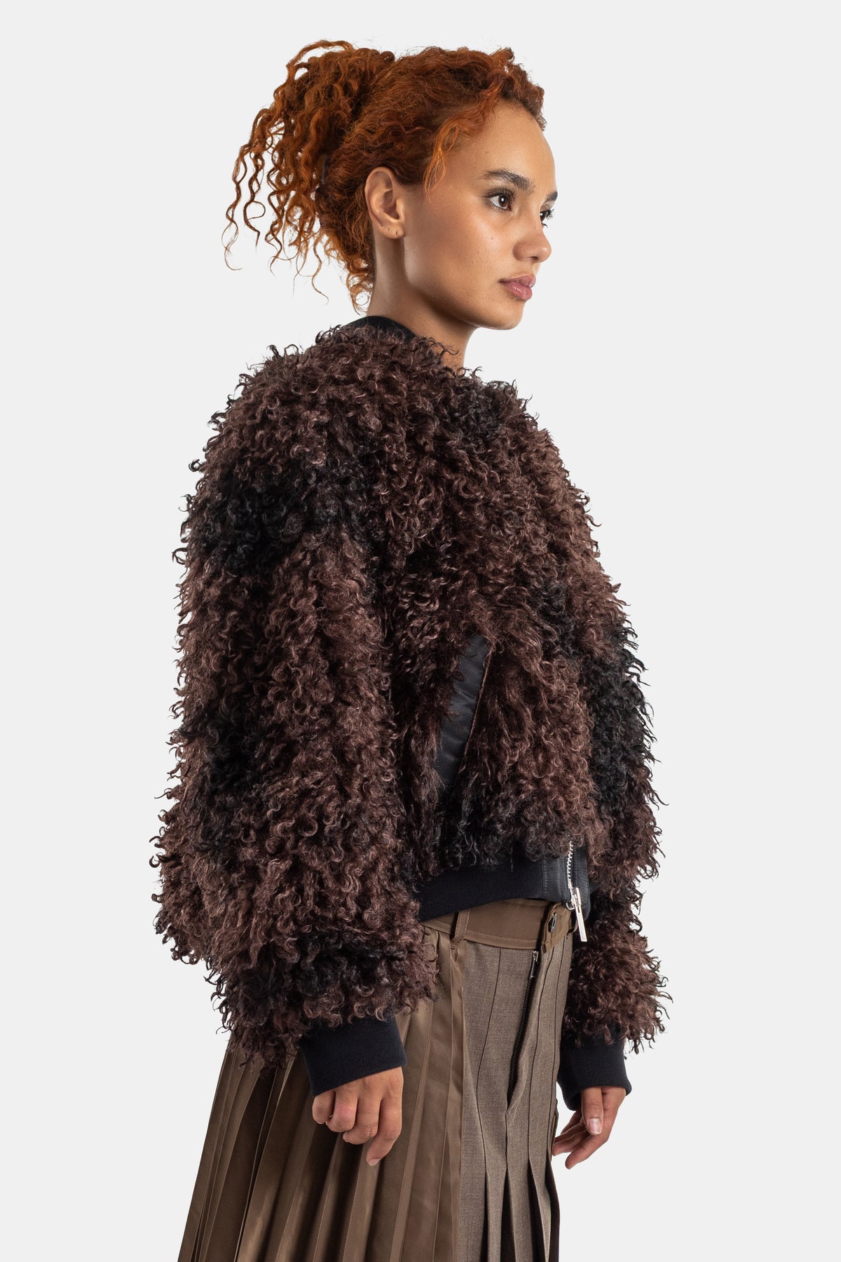 Bomber de mulher Sacai, vista de costas em pelo sintético encaracolado castanho, com gola e punhos pretos.