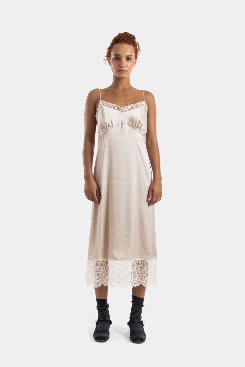 Vestido lencero Simone Rocha en satén marfil, corte imperio, tirantes finos y encaje floral a media pierna.