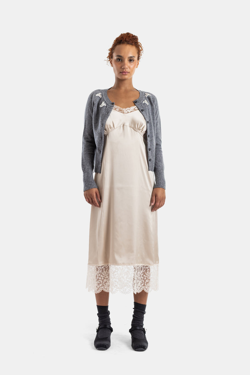 Look a capas Simone Rocha: cárdigan gris bordado de flores sobre vestido lencero marfil con bajo de encaje.