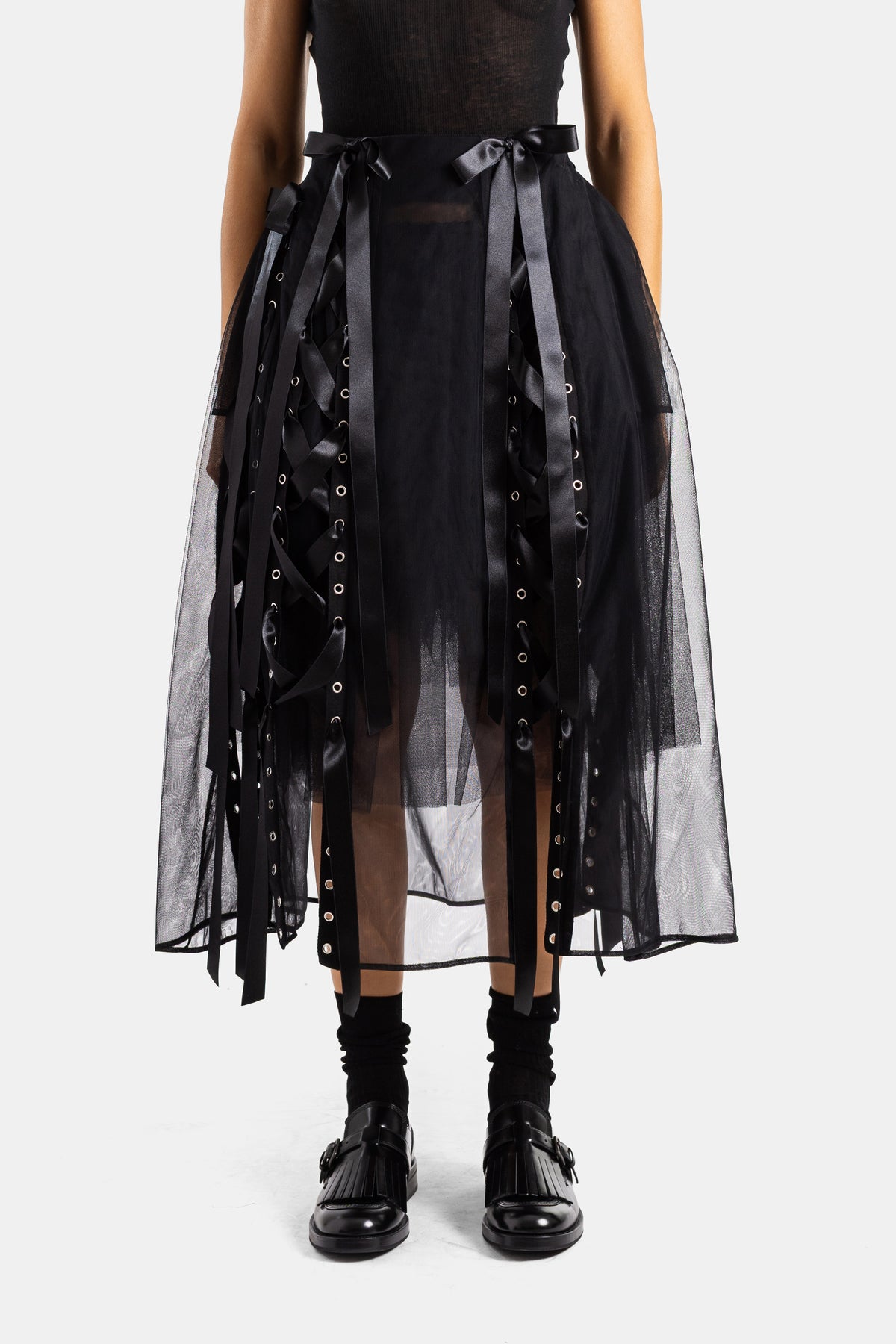 Gonna lunga firmata Simone Rocha in tulle nero trasparente con nastri in raso e occhielli metallici argentati.