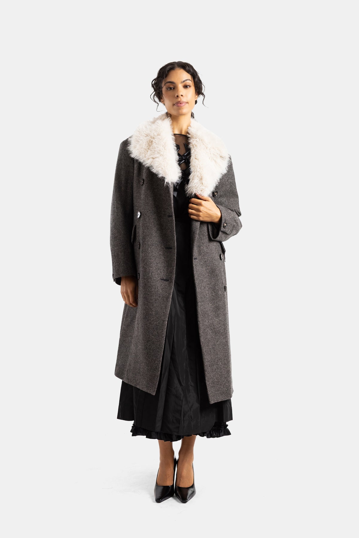 Simone Rocha double-breasted grey flecked wool coat with ivory shearling collar worn open over a ruffled black dress.