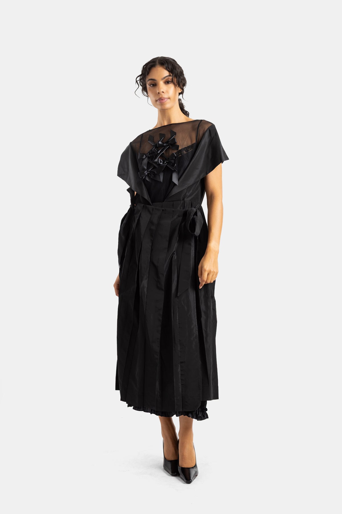 Simone Rocha black dress featuring embroidered satin bows, a sheer tulle boat neck and pleated midi skirt