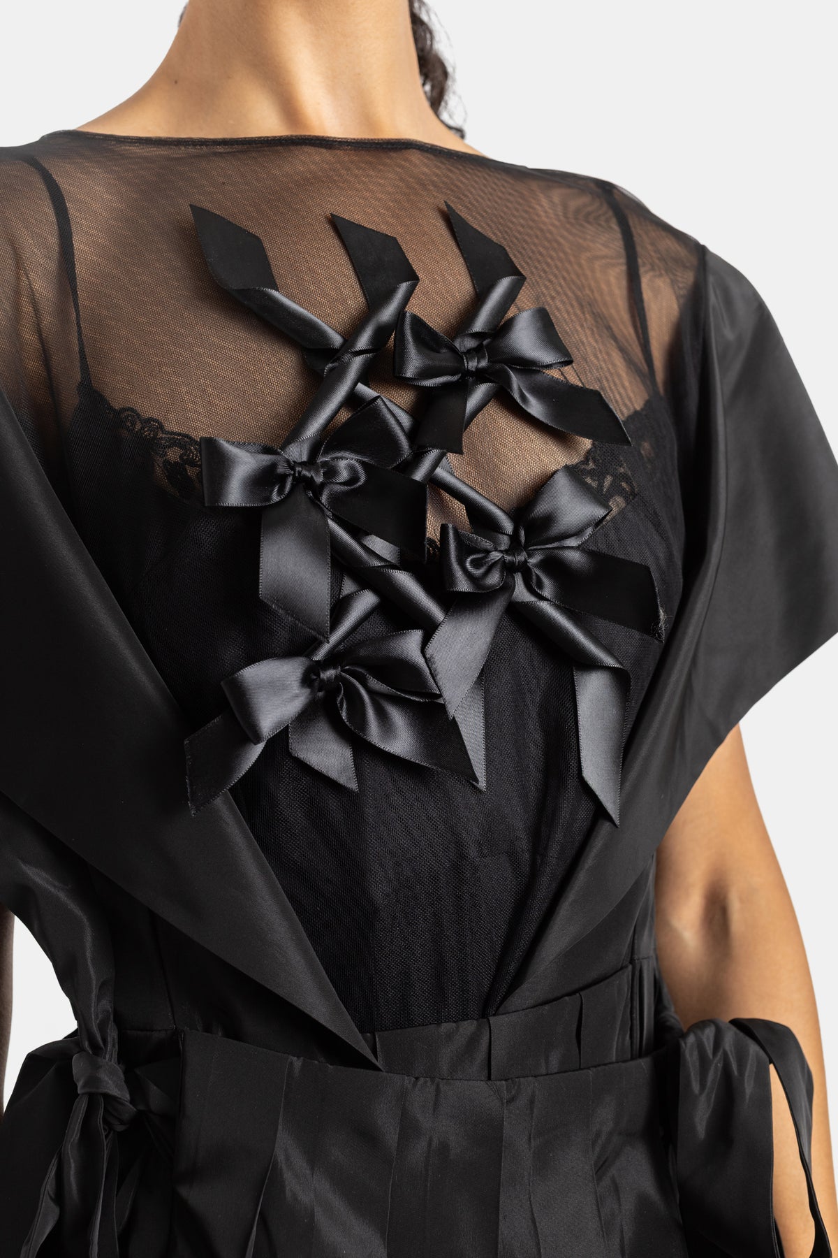 Back close-up of Simone Rocha black dress with satin bows on sheer tulle and a V-neck cutout detail
