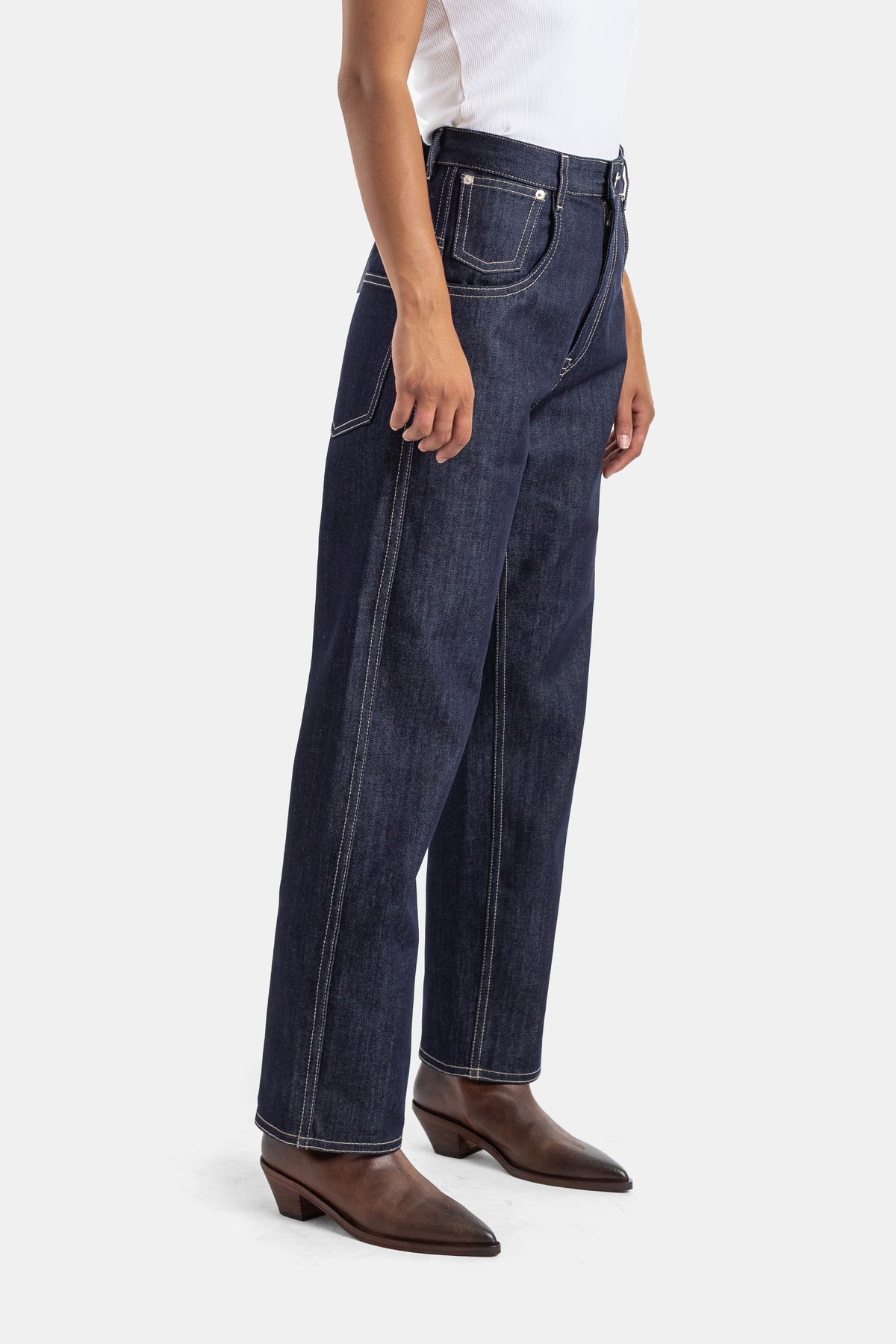 Sofie d'Hoore straight high-waisted raw denim jeans, side view with buckle belt and camel ankle boots