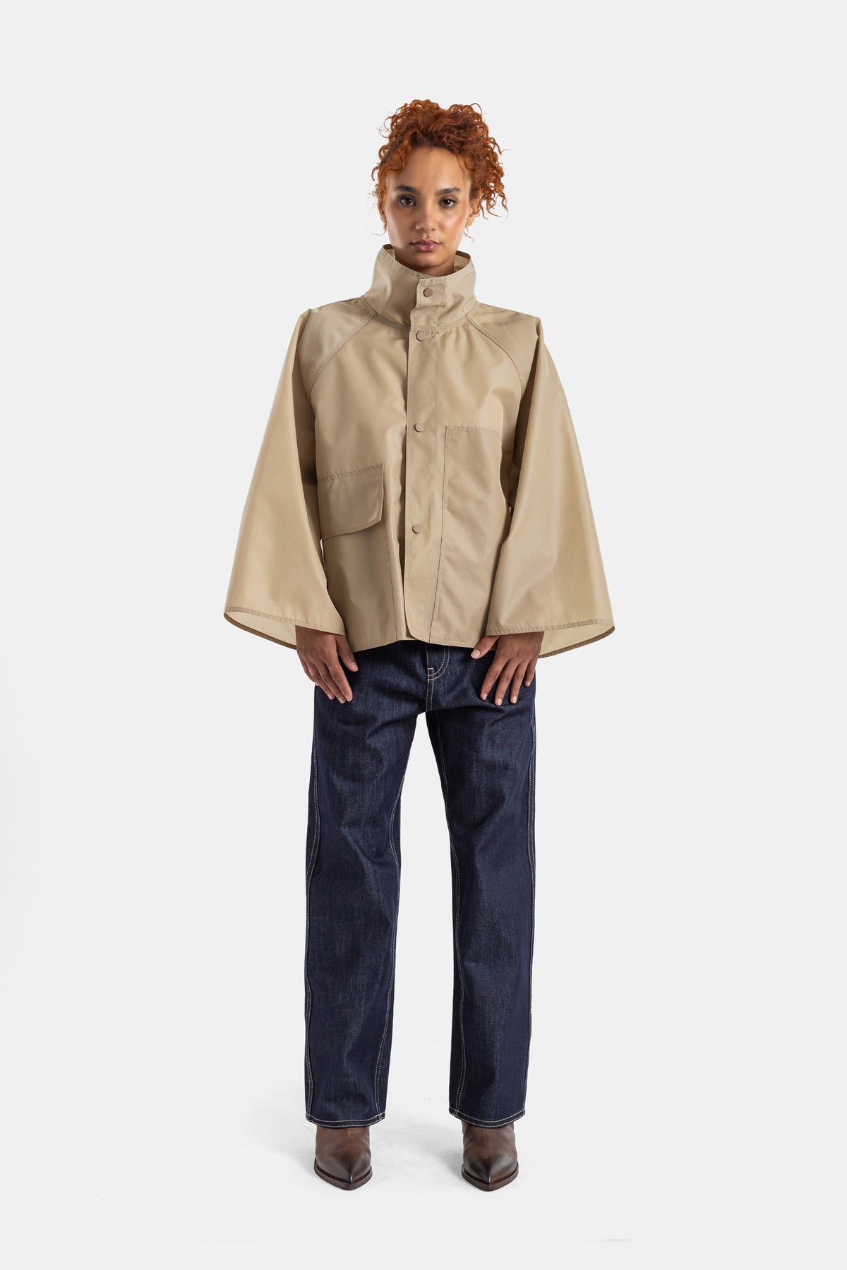 Sofie d'Hoore wide-leg raw denim jeans worn with a beige cape jacket and chocolate brown ankle boots