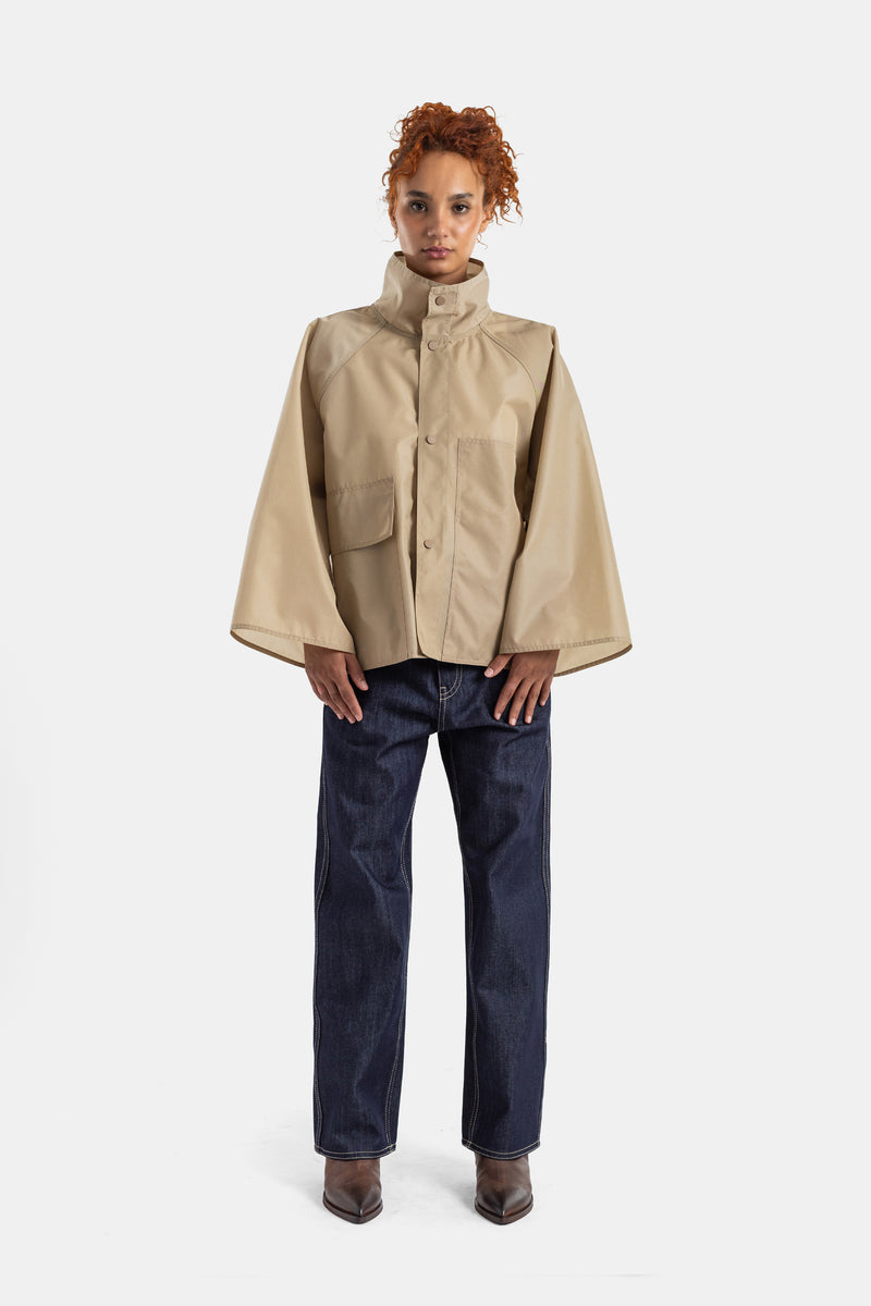 Sofie d'Hoore wide-leg raw denim jeans worn with a beige cape jacket and chocolate brown ankle boots