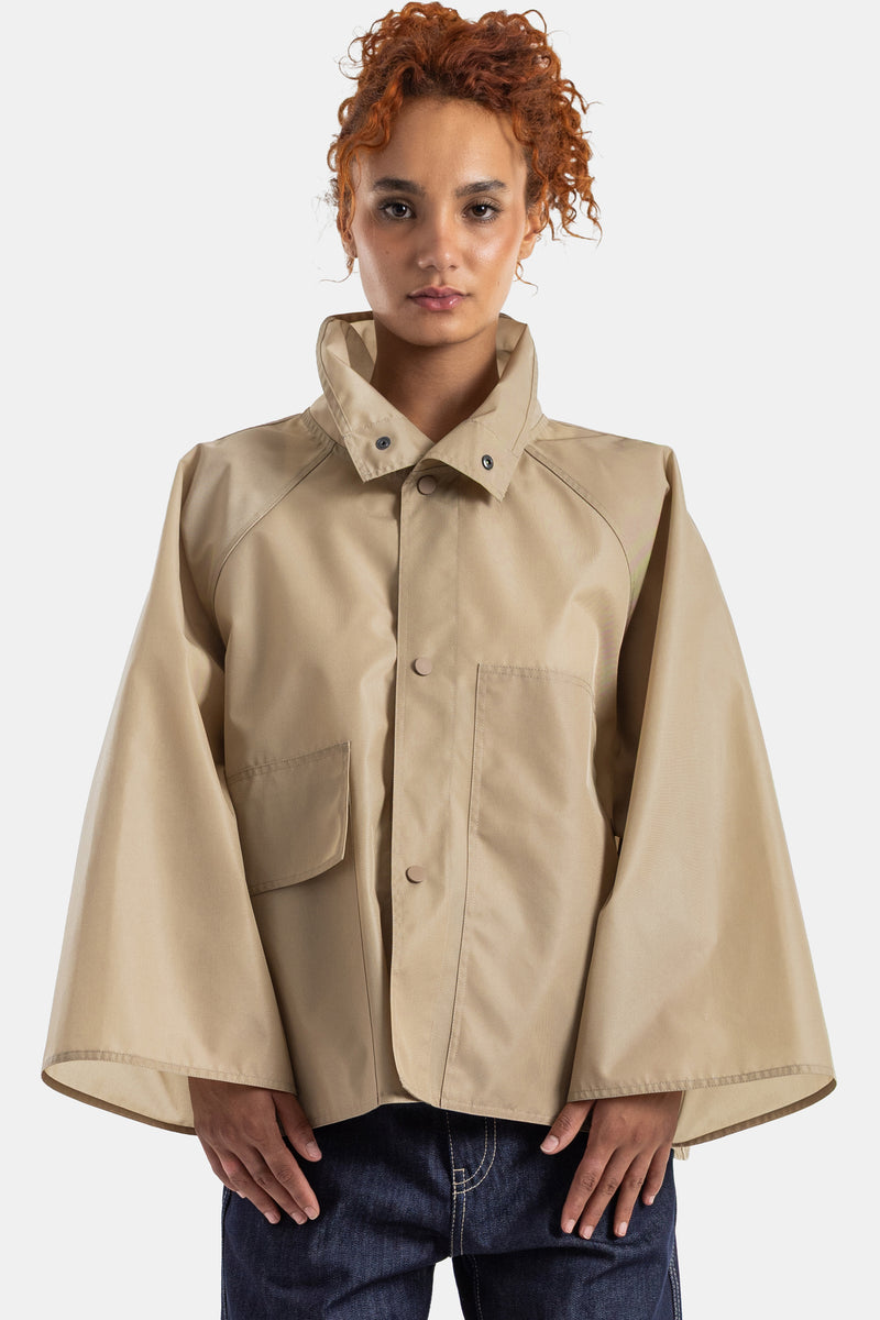 Sofie d'Hoore short beige jacket in technical cotton featuring a cape cut, high neck and wide sleeves.