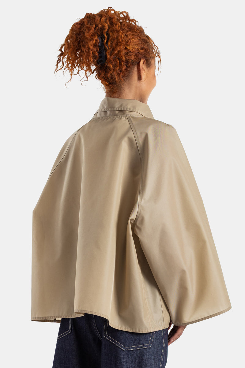 Sofie d'Hoore의 베이지 테크니컬 코튼 쇼트 재킷 뒷모습으로, 등 라인을 감싸는 볼륨감 넘치는 기모노 소매와 클래식한 칼라 디테일이 구조적이면서도 우아한 실루엣을 완성합니다.
