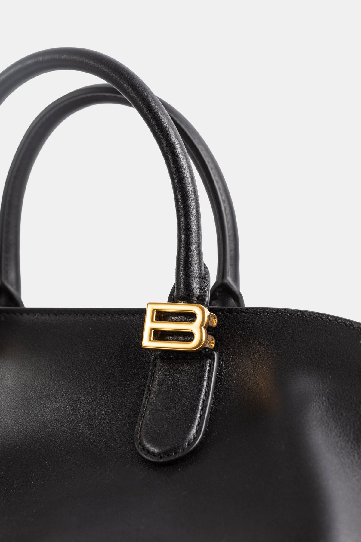 Balenciaga Bolero Bowling, gros plan fermoir BB doré sur languette cuir noir et doubles poignées tubulaires