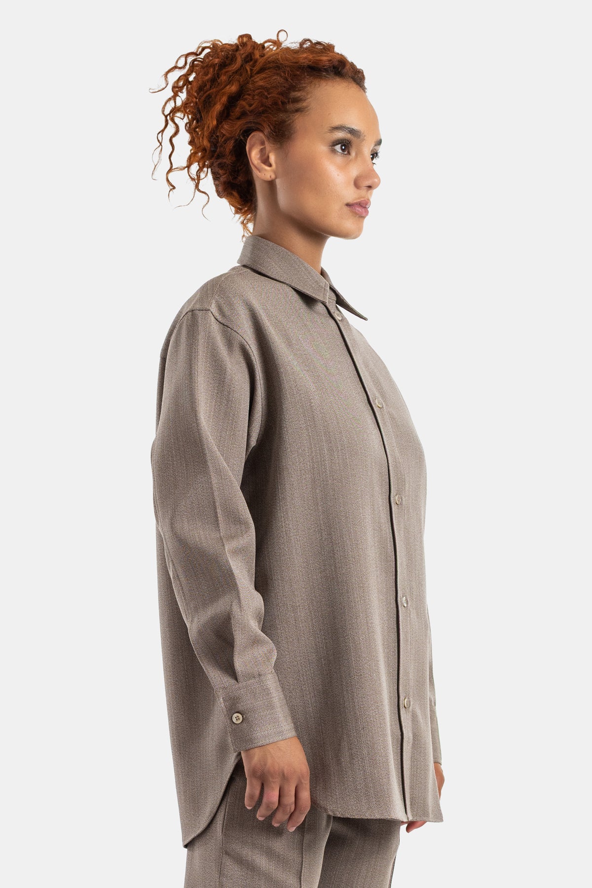 Studio Nicholson Damenhemd in Taupe in Profilansicht mit Perlmuttknöpfen, Oversize-Schnitt in Tunika-Länge.