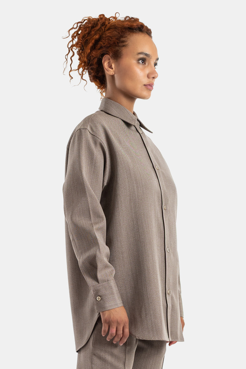 Studio Nicholson Damenhemd in Taupe in Profilansicht mit Perlmuttknöpfen, Oversize-Schnitt in Tunika-Länge.