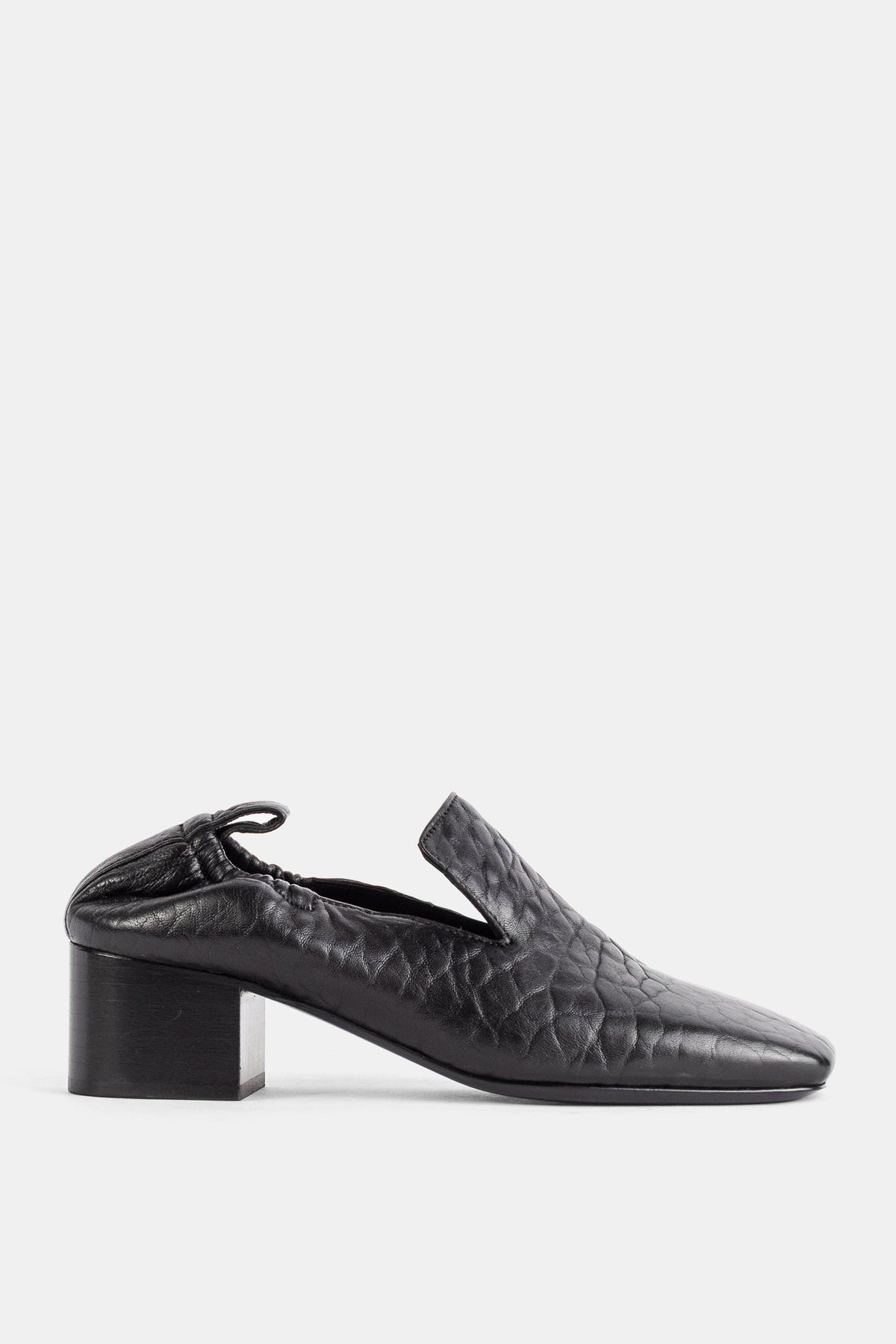 Studio NicholsonのMoonパンプス。ブラックのクリンクルレザーを使用したモカシンスタイルで、スクエアトゥと安定感のあるブロックヒール、特徴的なヒールカットが洗練されたモダンな足元を演出します。
