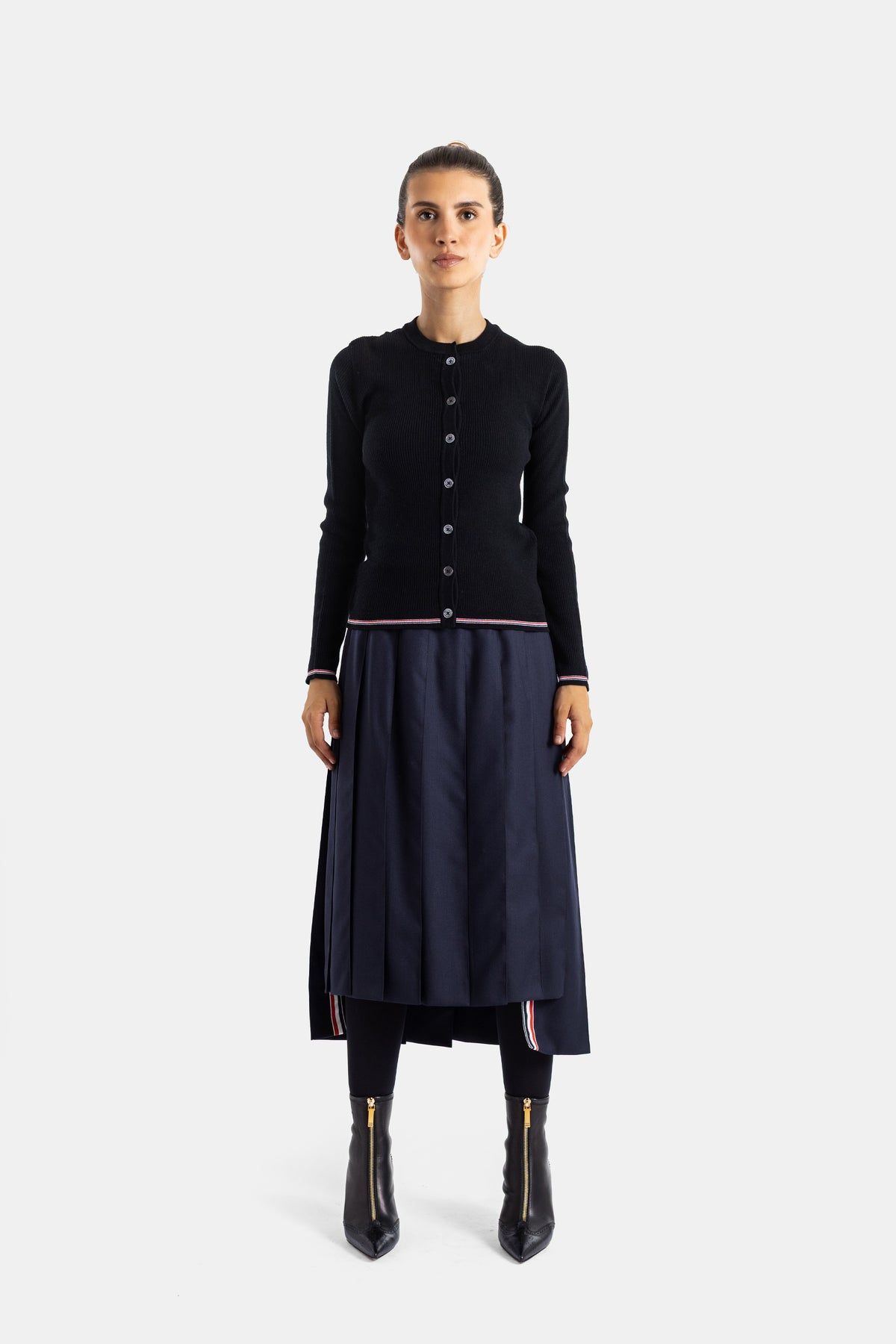 Thom Browne jupe plissée midi marine portée avec cardigan noir et bottines zippées, look complet face