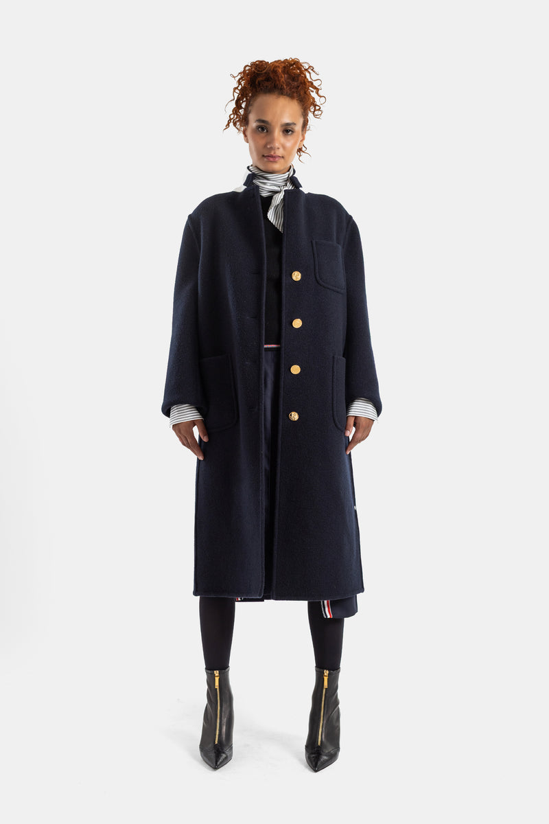 Cappotto Thom Browne in lana cotta blu navy con iconici bottoni dorati e sciarpa a righe su leggings neri