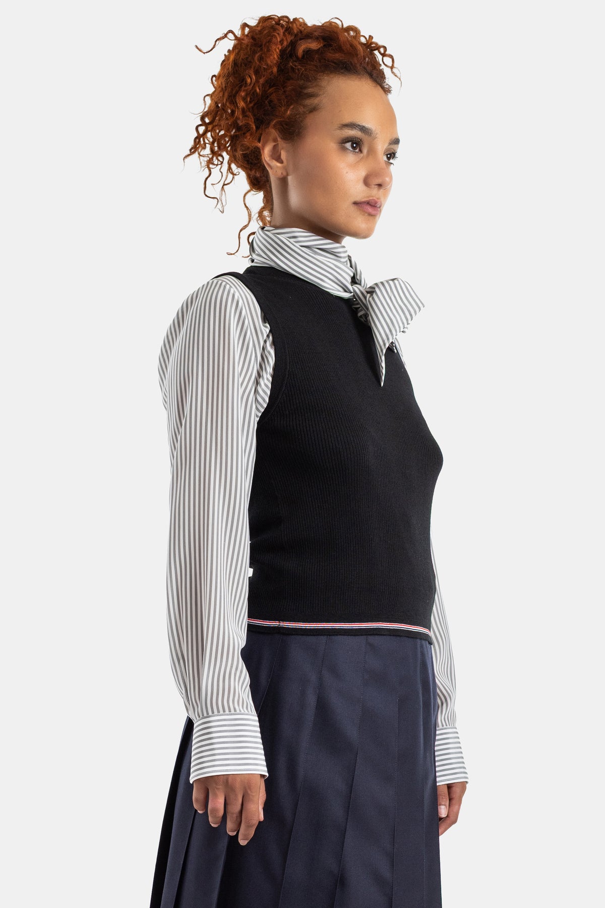 Thom Browne vue de profil top côtelé noir sans manches superposé sur chemise rayée grise et blanche femme