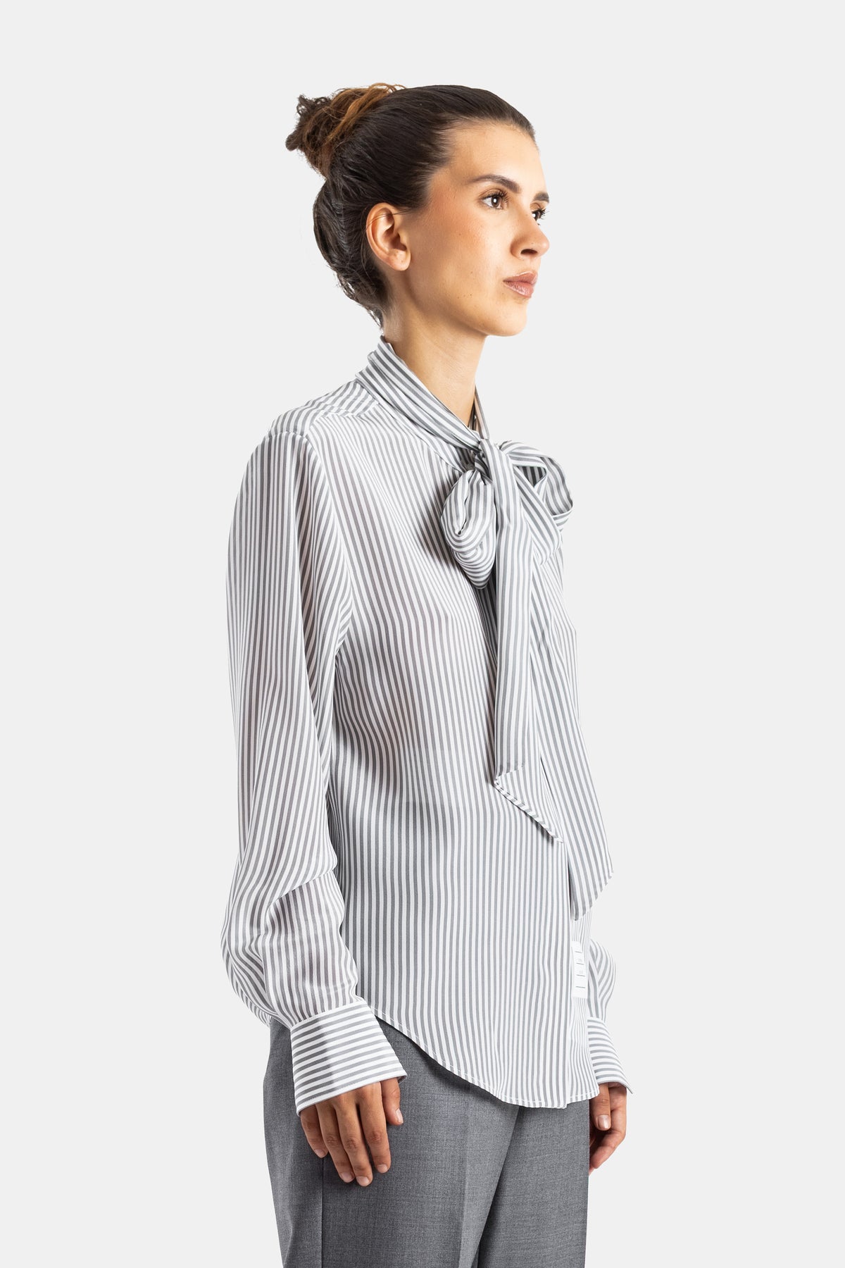 Thom Browne blouse soie rayée profil vue côté nœud lavallière tombant poignet boutonné pantalon gris femme