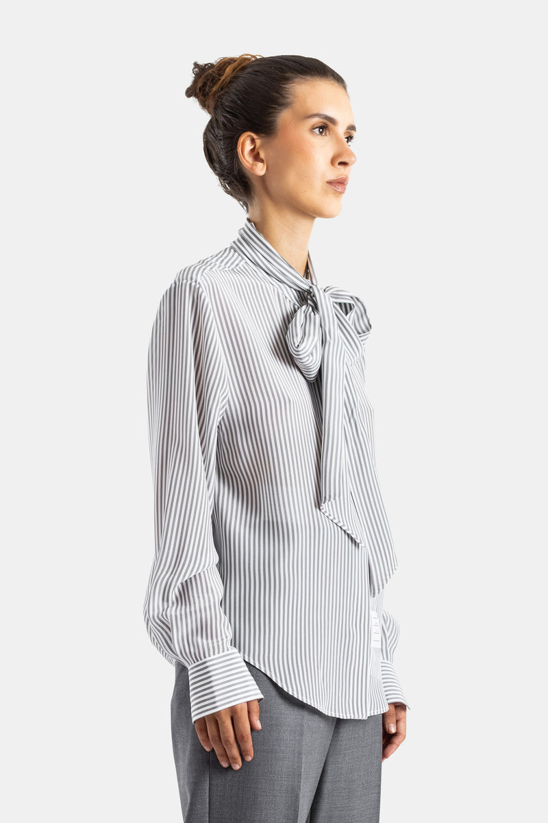 Thom Browne blouse soie rayée profil vue côté nœud lavallière tombant poignet boutonné pantalon gris femme