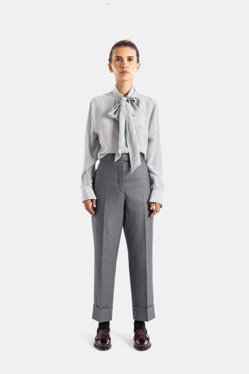 Thom Browne chemise soie rayée lavallière nouée portée avec pantalon tailleur gris et mocassins bordeaux femme