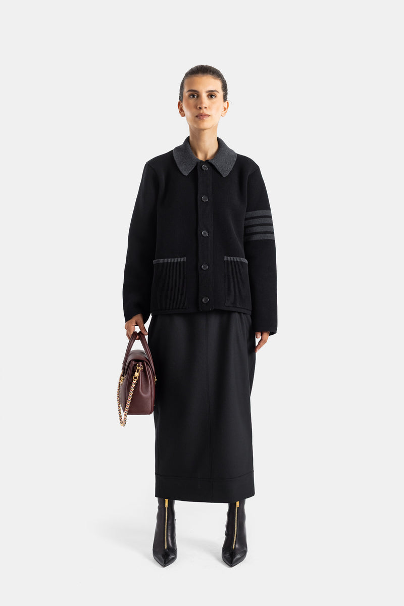 Thom Browne look total black femme veste maille polo et jupe mi-longue portés avec boots et sac cuir bordeaux