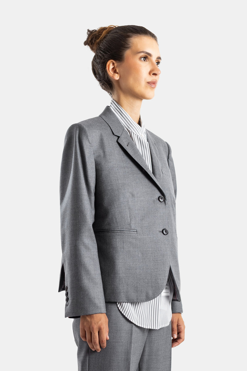 Thom Browne blazer femme laine grise profil, chemise rayée visible, boutons noirs et poches passepoilées